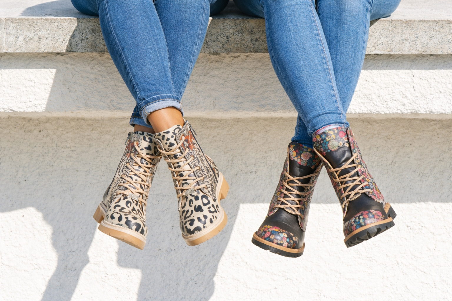 Two pairs of patterned boots worn by people sitting on steps.